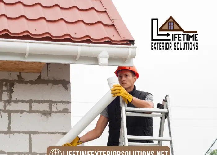 A man is installing gutters in a roof with siding by Lifetime Exterior Solutions gutters installation services in WA